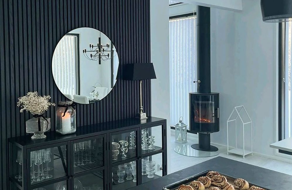 A black and white living room featuring a fireplace, a table, and a striking black accent wall for added elegance.