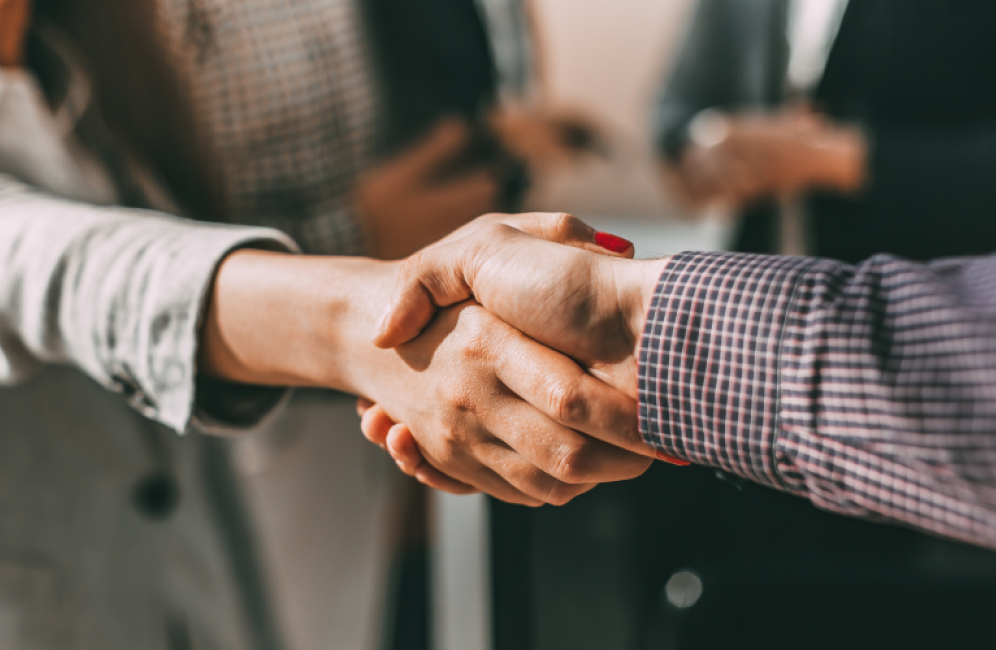 Business professionals shaking hands in an office setting, showcasing collaboration and the premium hexagon acoustic panel design.