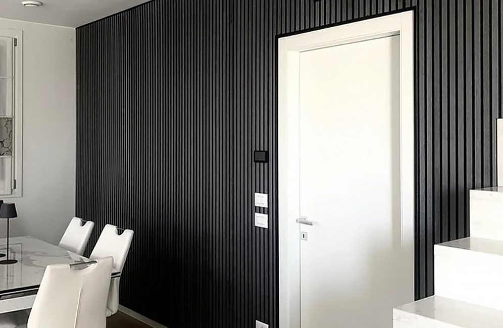 A sophisticated dining room in black and white, highlighted by a black accent wall and chic white chairs.