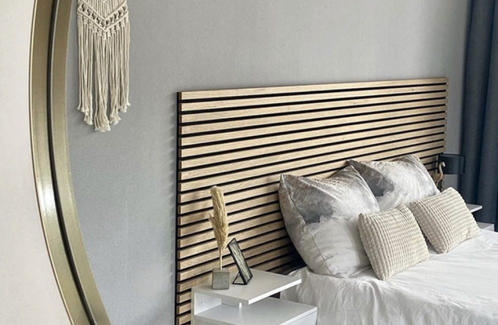 A cozy bedroom featuring a round mirror above a bed, complemented by a stylish accent wall.